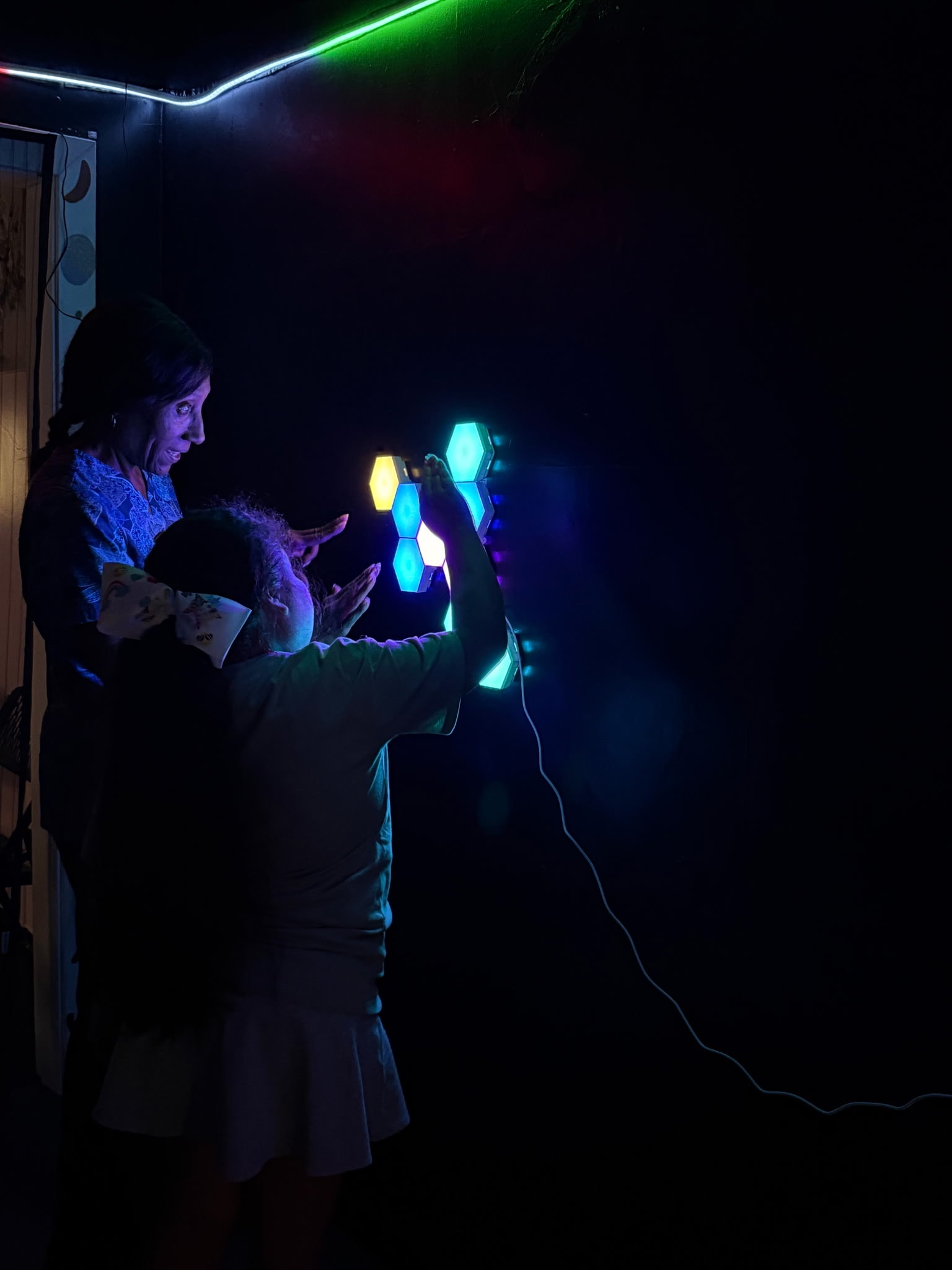 People interacting with colorful hexagonal lights